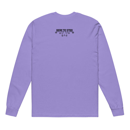Violet, long-sleeve shirt. Featuring the phrase ‘Queer existence is the agenda’ on the front, ‘here to stay’ on the back. Design is in black, with a butterfly design on the front and an abstract design on the back. Design is in contrast to legislation that is based on eraser of queer people. Designed by a small LGBTQ+ owned business. Back of shirt.