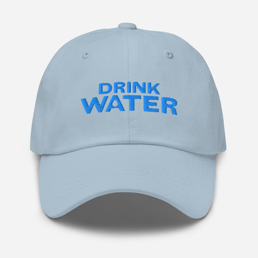 Light blue classic dad hat with bright blue text that reads ‘DRINK WATER’ designed by queer creators to express the need to remember to stay hydrated. Front view, not on model. 