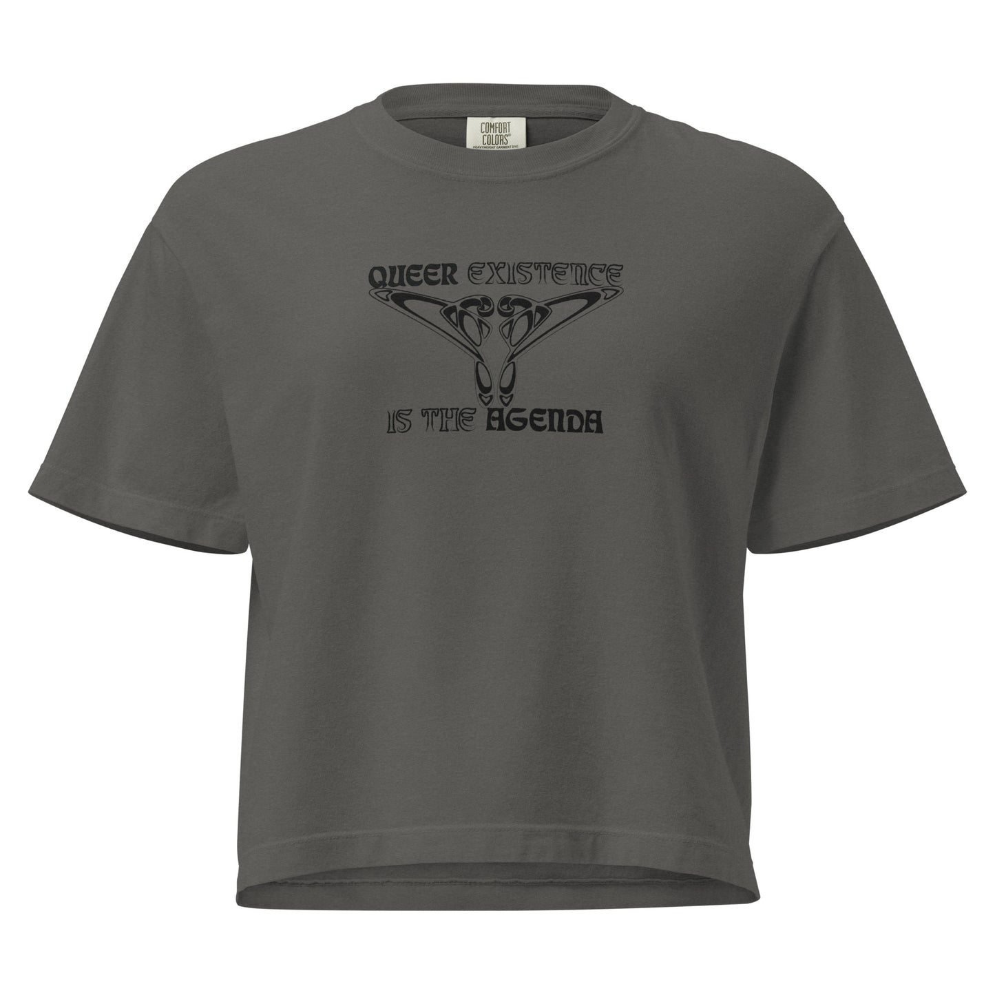 Pepper, boxy t-shirt. Featuring the phrase ‘Queer existence is the agenda’ on the front, ‘here to stay’ on the back. Design is in black, with a butterfly design on the front and an abstract design on the back. Design is in contrast to legislation that is based on eraser of queer people. Designed by a small LGBTQ+ owned business. Front of shirt. 