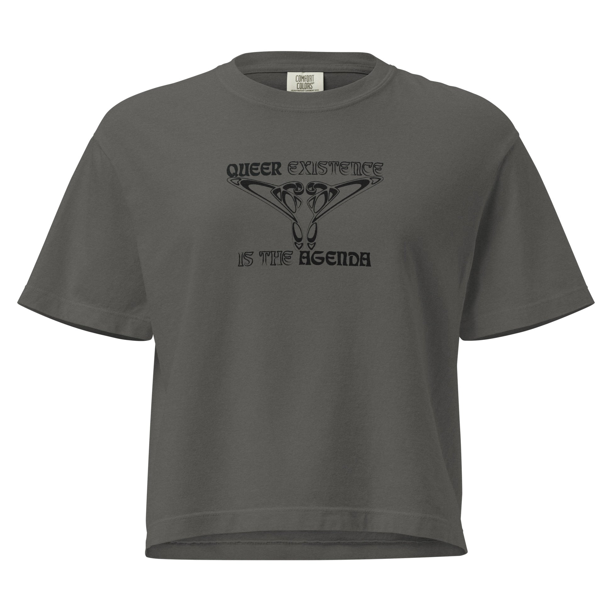 Pepper, boxy t-shirt. Featuring the phrase ‘Queer existence is the agenda’ on the front, ‘here to stay’ on the back. Design is in black, with a butterfly design on the front and an abstract design on the back. Design is in contrast to legislation that is based on eraser of queer people. Designed by a small LGBTQ+ owned business. Front of shirt. 