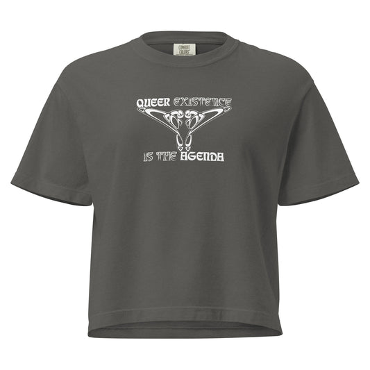 Pepper, boxy t-shirt. Featuring the phrase ‘Queer existence is the agenda’ on the front, ‘here to stay’ on the back. Design is in white, with a butterfly design on the front and an abstract design on the back. Design is in contrast to legislation that is based on eraser of queer people. Designed by a small LGBTQ+ owned business. Front of shirt. 