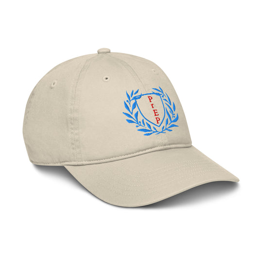 Oyster colored hat, front text reading ‘PrEP’ in red, blue leaves styled in Ivy League-inspired design. Made by queer creators to promote HIV awareness and access to PrEP through unapologetic activism and education. Side view, not on model.