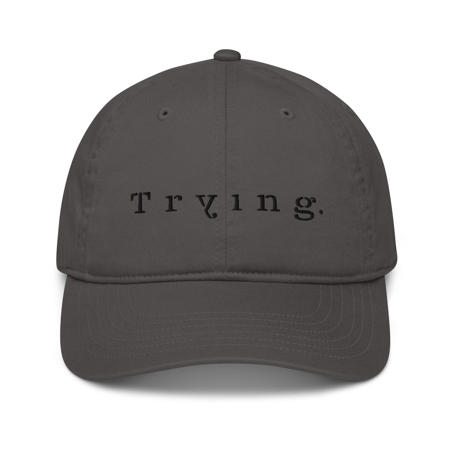 Charcoal dad hat embroidered with the word "Trying." in spaced serif lettering — a 12:AM Intuition design honoring the messy middle. 